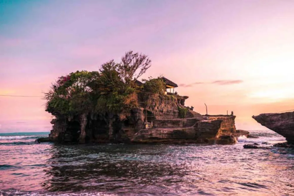 Świątynia Tanah Lot na skale otoczonej wodą o zachodzie słońca